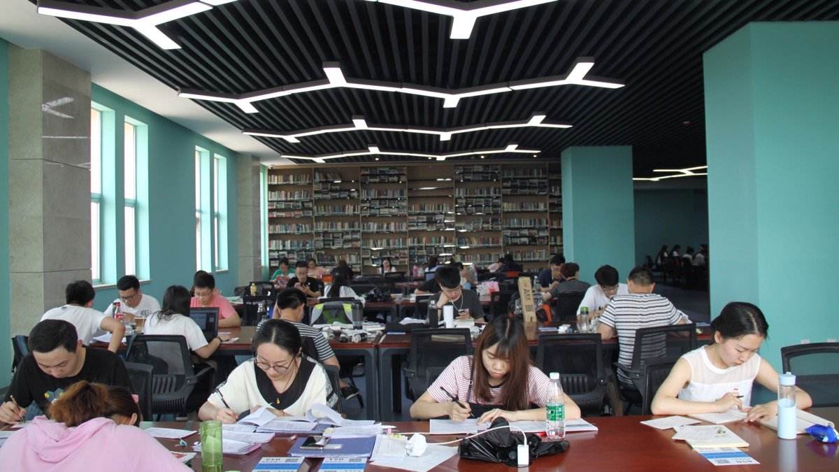 圖書館內多名學生分散坐著閱讀、寫筆記與使用電腦